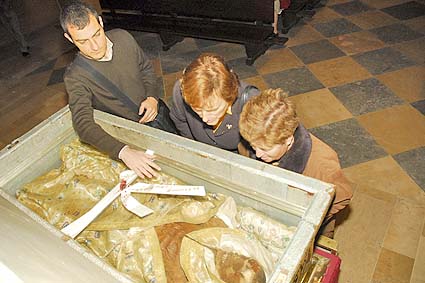 A devoted Catholic family looks at the corpse inside the silver box. 