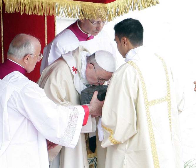 The Pope bows, and kisses the box with the bones. 
